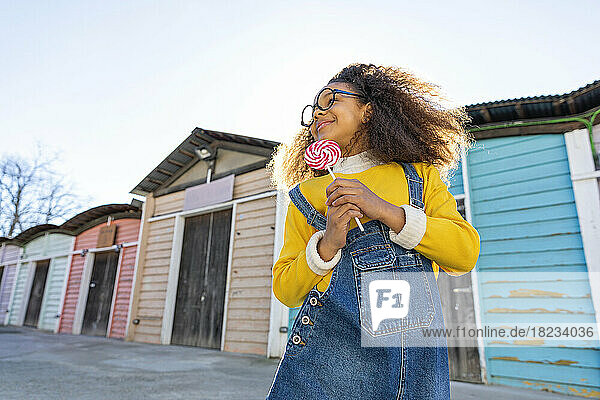 Girl with lollipop in front of beach huts