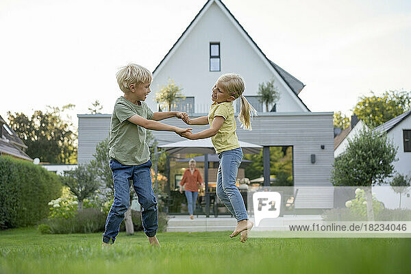 Glückliches Mädchen und Junge  die im Garten spielen