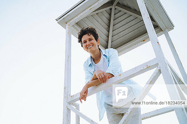 Smiling androgynous woman looking from lifeguard hut
