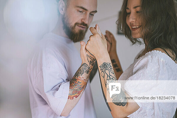 Happy hipster couple with tattoo on hands dancing together