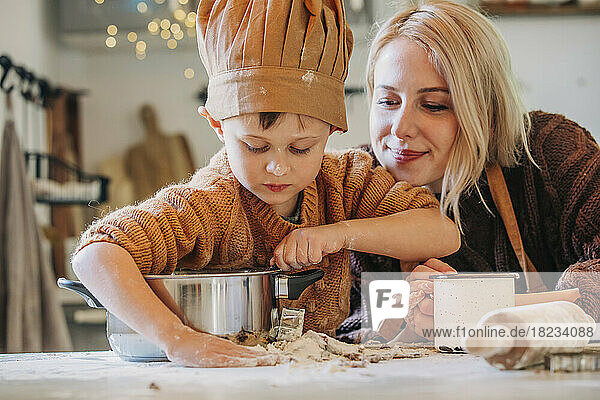 Smiling woman with son preparing cookies at home