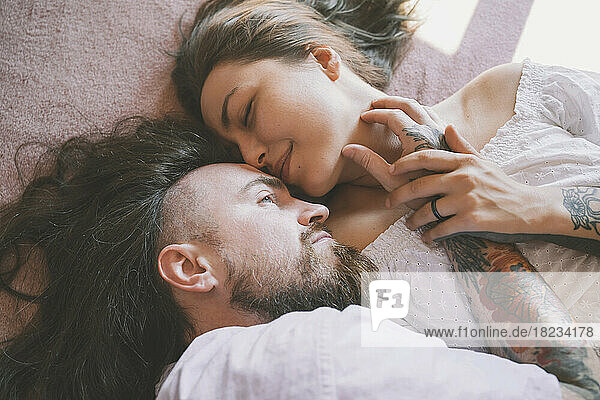 Romantic hipster couple lying on bed at home