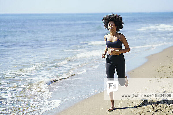 Junge Frau läuft an einem sonnigen Tag am Strand