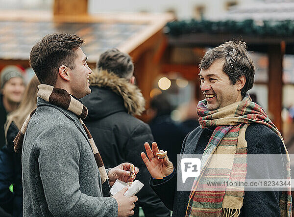 Happy father talking to son standing at Christmas market