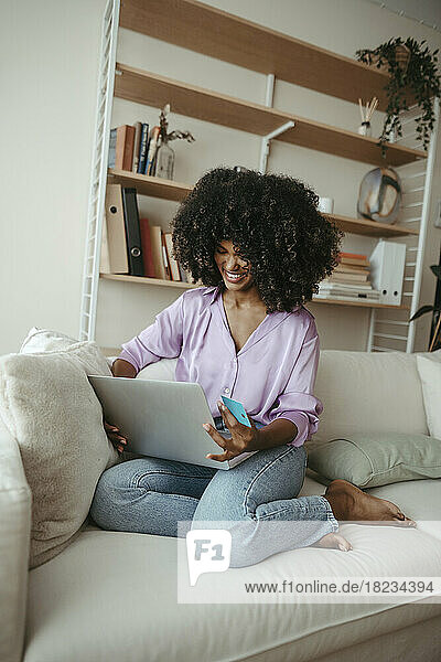 Happy woman doing online shopping on laptop in living room