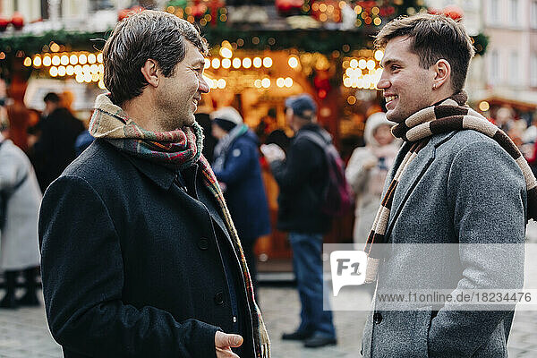 Smiling mature man talking with son standing at Christmas market
