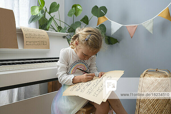 Blondes Mädchen schreibt zu Hause auf Notenblatt