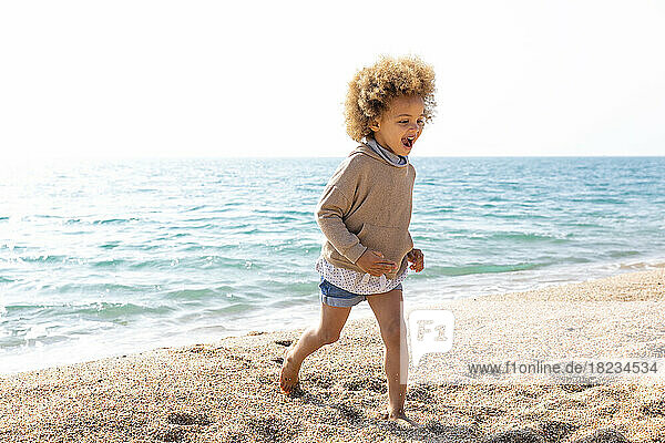 Cheerful girl running in front of sea at beach
