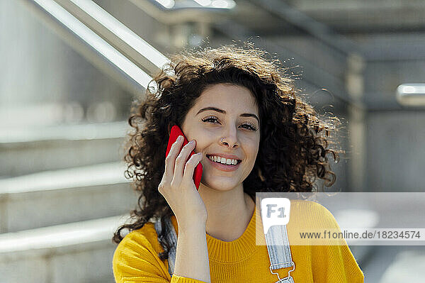 Beautiful woman with curly hair talking on mobile phone