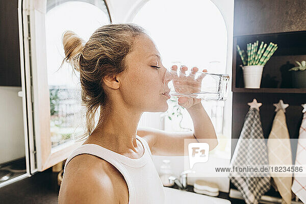 Woman drinking water from a glass in the kitchen