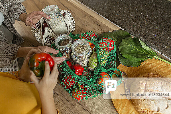 Grandmother and granddaughter unpacking fresh groceries in kitchen