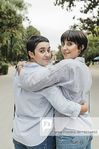 Lesbische Frauen mit umarmten Armen schauen über die Schulter in den Park