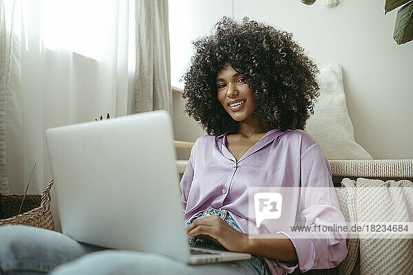 Smiling Afro woman with laptop at home