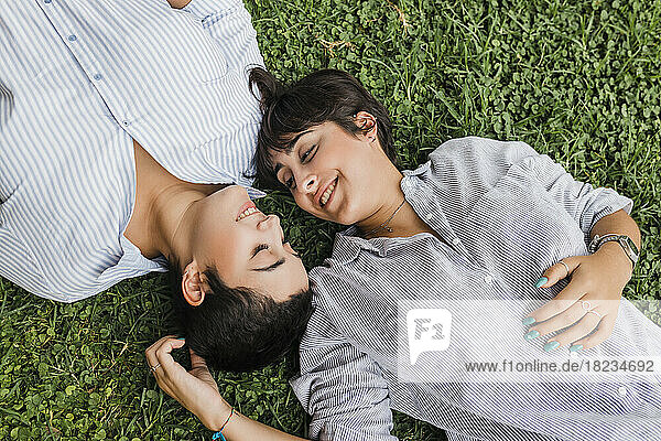 Romantic lesbian couple spending leisure time lying on grass