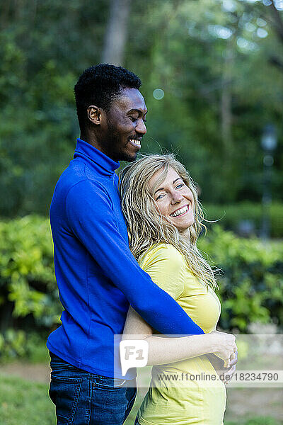 Smiling boyfriend embracing girlfriend in park