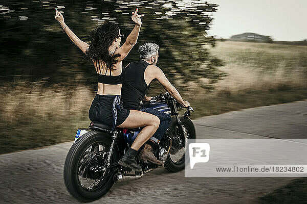 Woman enjoying with man riding motorcycle on road