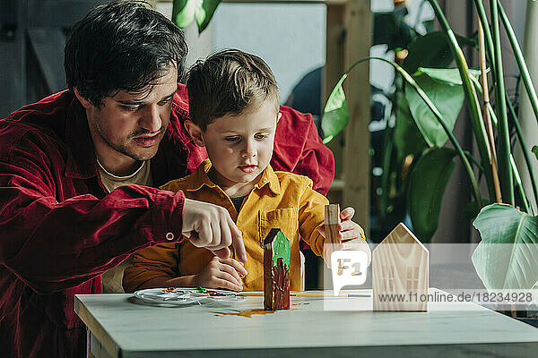 Vater und Sohn malen zu Hause gemeinsam Holzhäuser