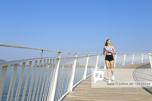 Happy young woman jogging on elevated walkway