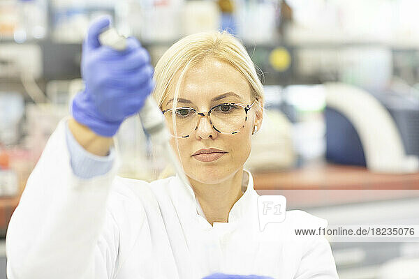 Scientist with pipette examining medical sample at laboratory