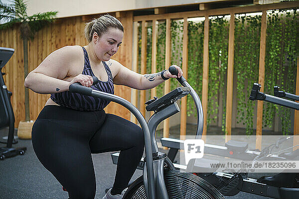 Overweight woman doing workout on cross trainer in gym