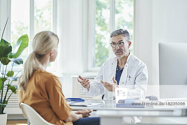 Doctor discussing with patient sitting at desk in medical practice