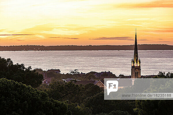 France  Nouvelle-Aquitaine  Arcachon  View of seaside town at sunset with Notre-Dame Basilica in foreground