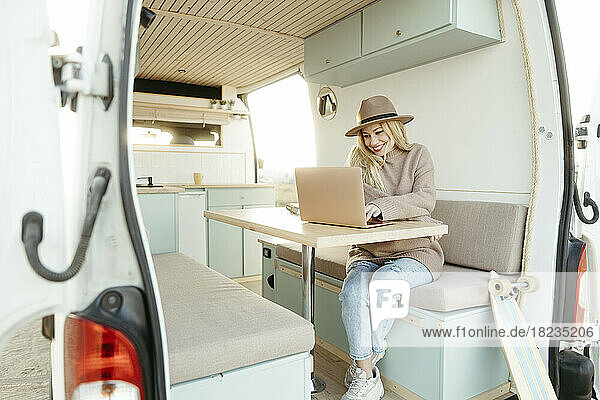 Happy freelancer working on laptop sitting in motor home