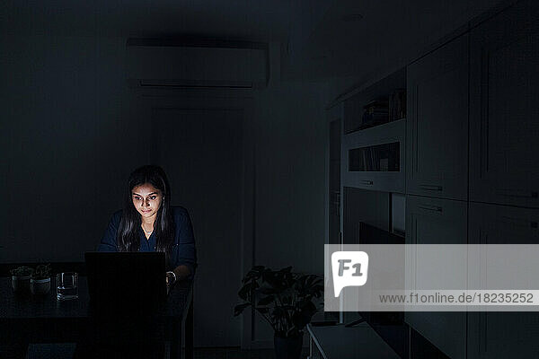 Junge Frau benutzt Laptop im Wohnzimmer zu Hause