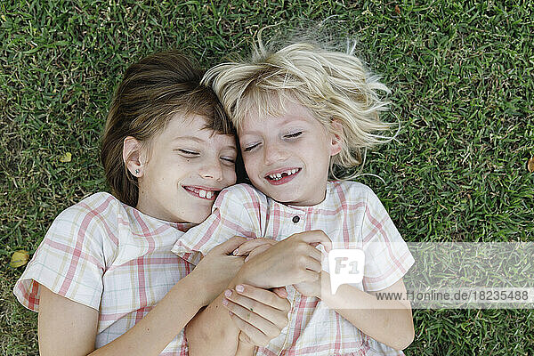 Smiling girl with sister lying on grass