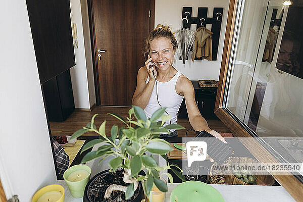 Glückliche Frau am Telefon  aufgeladen durch Solarbatterie in der Küche