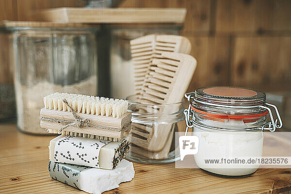 Stack of soap bars and scrubbing brush with hair combs and jar on table