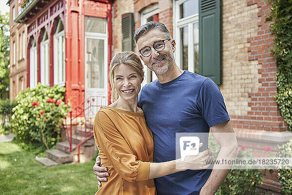 Lächelnde Frau umarmt Mann vor Haus