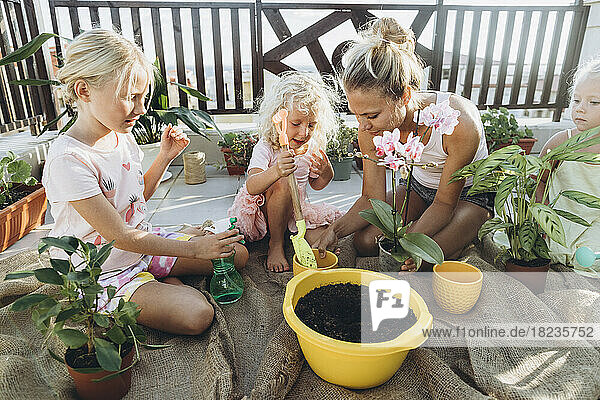 Mother and daughters planting flowers on roof terrace together