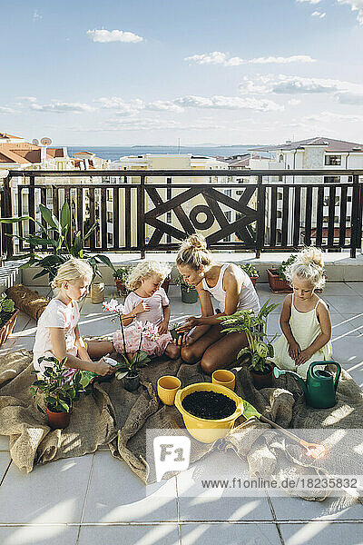 Mother and daughters planting flowers on roof terrace together