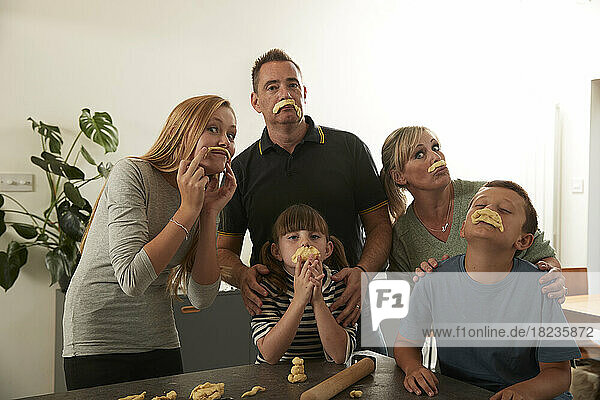 Playful family with dough mustaches at home