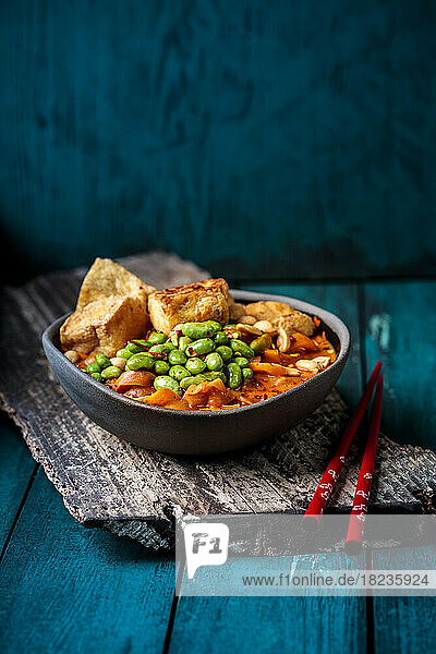 Schüssel mit verzehrfertigem veganem Curry mit Edamame und Tofu