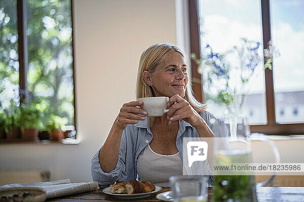Reife Frau hält zu Hause eine Tasse Kaffee