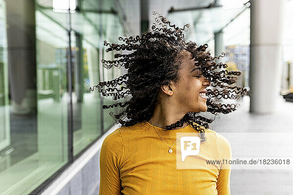 Carefree woman tossing hair on footpath