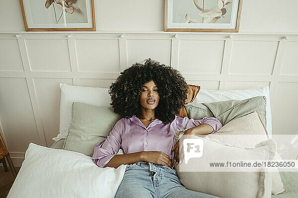 Woman amidst pillows relaxing on bed at home