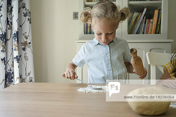 Smiling girl with flour on table at home