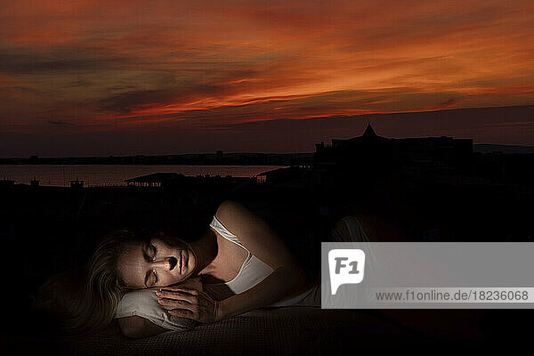 Frau mit geschlossenen Augen schläft bei Sonnenuntergang