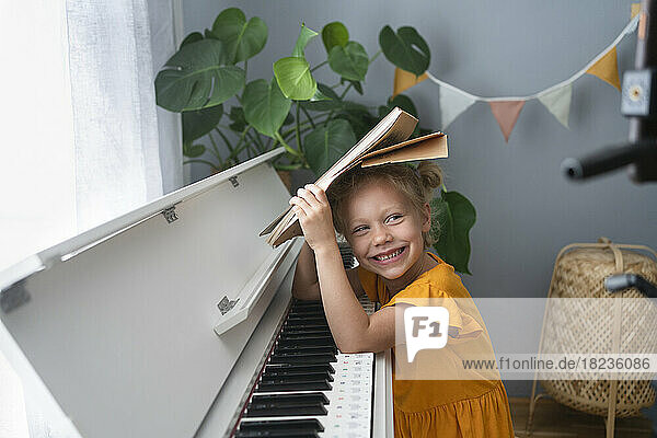 Cute smiling girl with musical notes at piano at home
