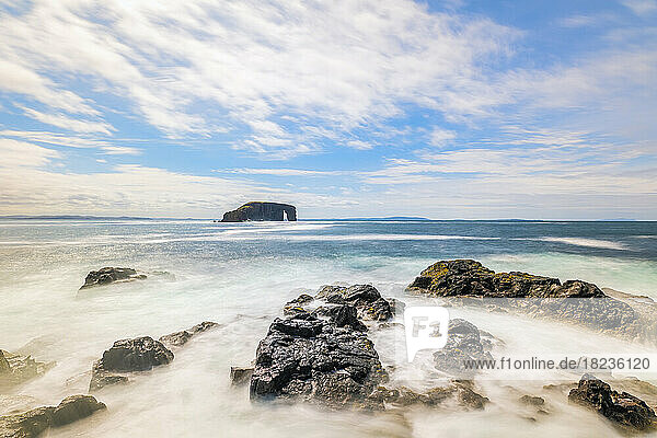 UK  Scotland  Rocky shore of Northmavine with Dore Holm arch in background