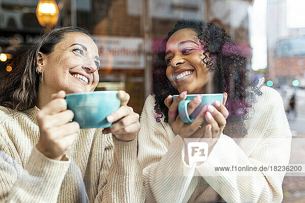 Glückliche Frauen genießen Kaffee im Café  gesehen durch Glas