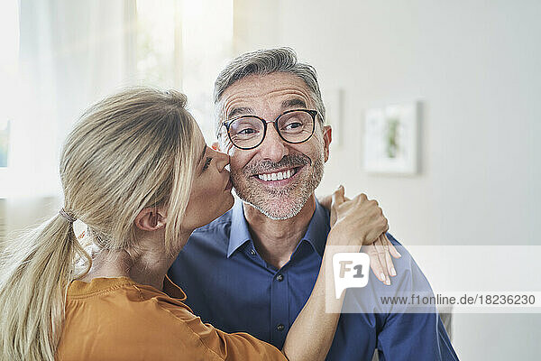Woman kissing happy man at home