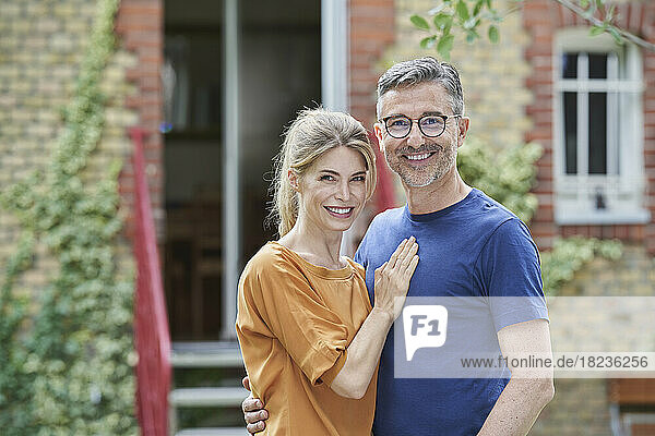 Lächelndes Paar  das sich vor dem Haus umarmt