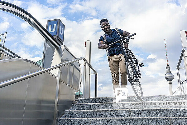 Smiling man carrying bicycle on steps
