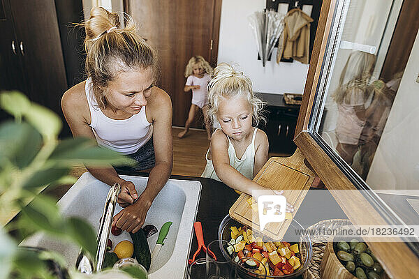 Mutter und Tochter bereiten gemeinsam in der Küche einen Salat zu