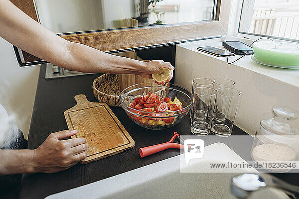 Frau bereitet in der Küche einen Salat zu und drückt Zitrone aus