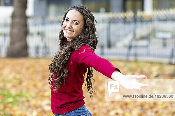 Smiling woman with arms outstretched in park